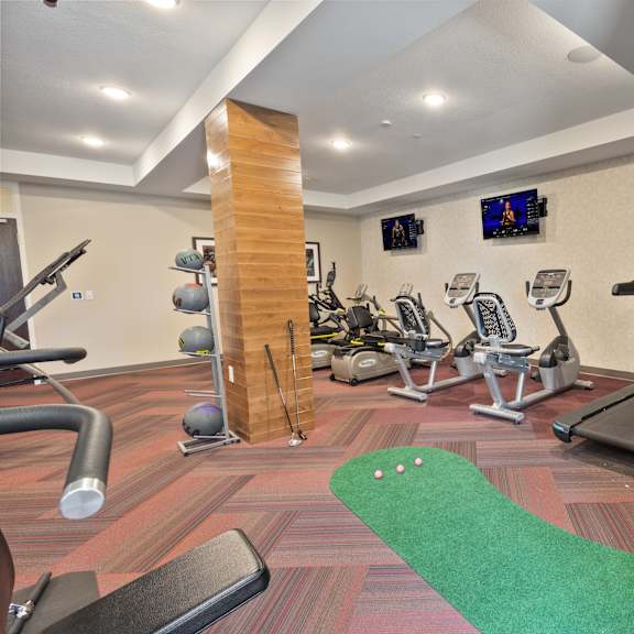 a gym with treadmills and weights and a green rug at the winslow 62+ apartments, minnesota, 55118