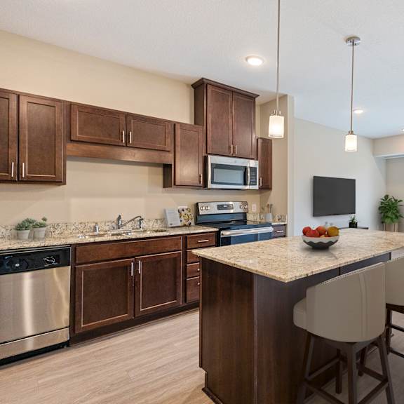 a kitchen and living room with a large island with a granite counter top at the winslow 62+ apartments, west st paul, 55118