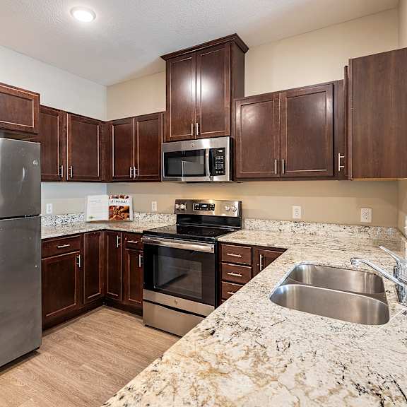 a kitchen with stainless steel appliances and marble counter tops at the winslow 62+ apartments, west st paul