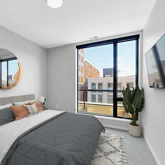 Thumbnail 7 of 12 A bedroom with a large bed and a flat screen TV mounted on the wall.