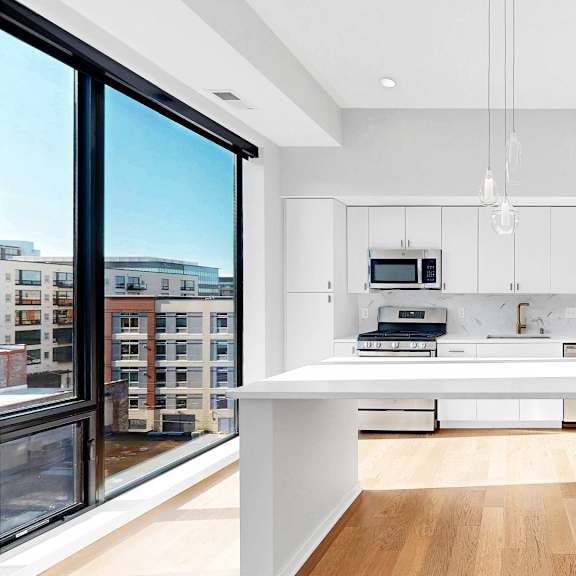 Thumbnail 8 of 12 A modern kitchen with white cabinets and a large island.