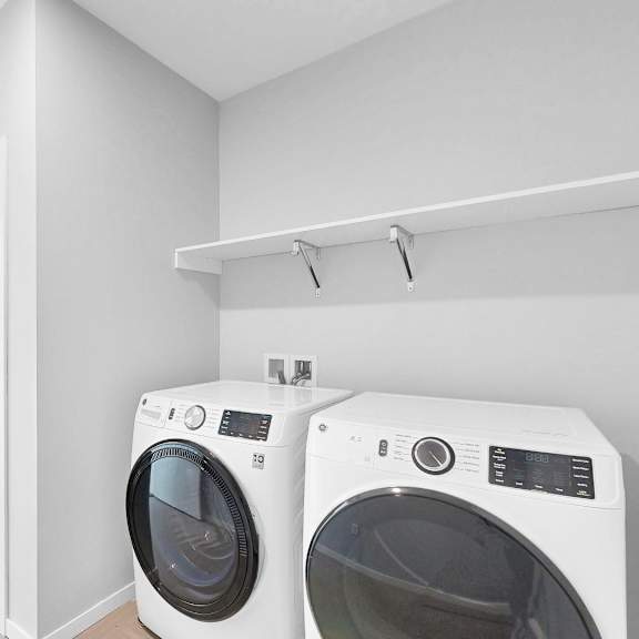 Thumbnail 11 of 12 Two front load washing machines in a laundry room.