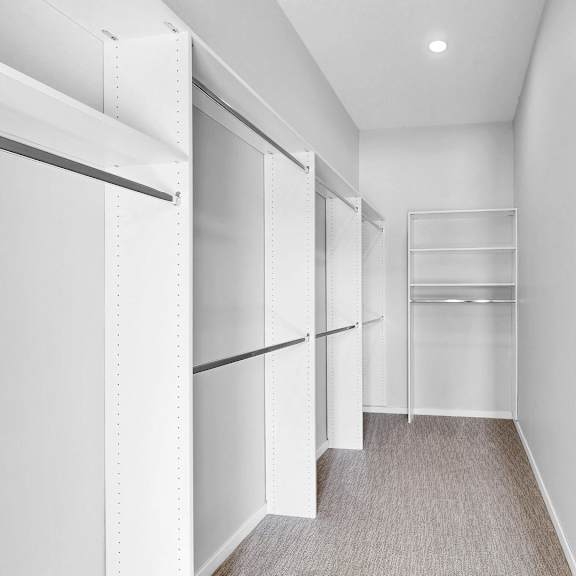 Thumbnail 10 of 12 A long hallway with white walls and a grey carpet.