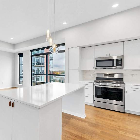Thumbnail 6 of 13 A modern kitchen with white cabinets and a large island.