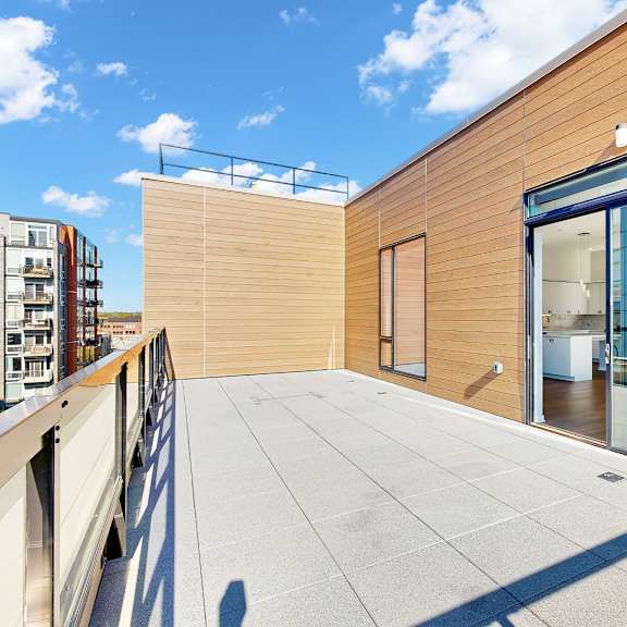 Thumbnail 12 of 12 A modern balcony with a glass door and a wooden wall.