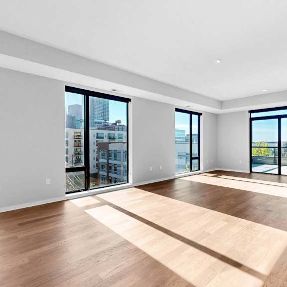 Thumbnail 9 of 12 A spacious room with wooden floors and large windows overlooking the city.