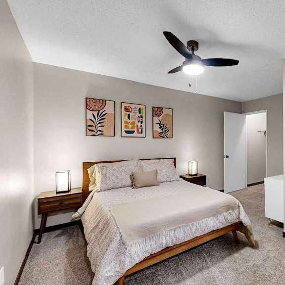 Thumbnail 7 of 9 A bedroom with a bed, a chair, and a ceiling fan.