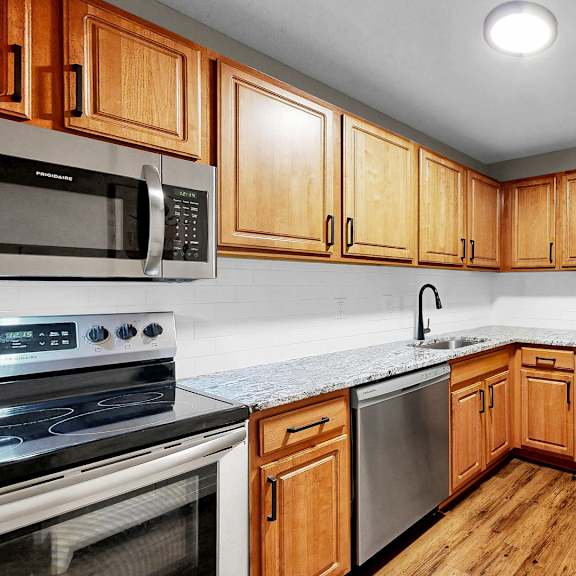 Thumbnail 5 of 9 A kitchen with wooden cabinets and a stainless steel refrigerator.