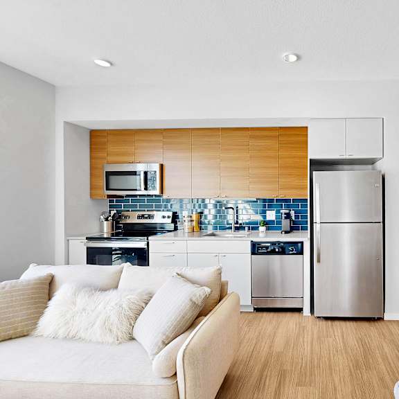 Thumbnail 5 of 10 A modern kitchen with a white couch and wooden accents.
