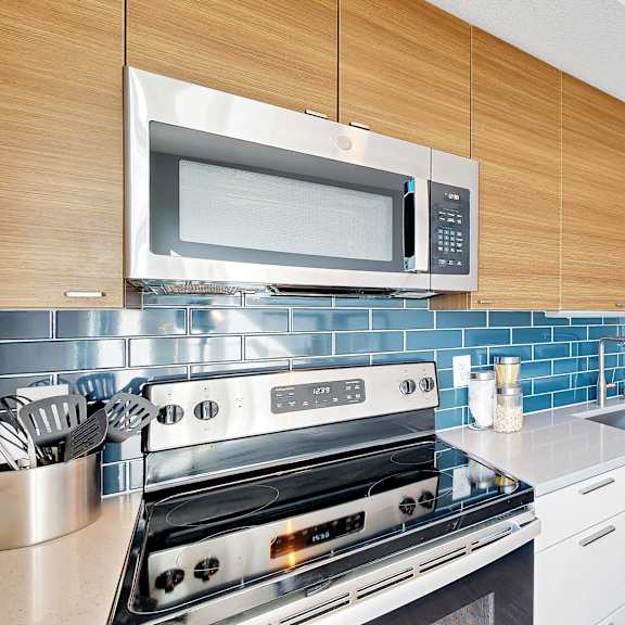 Thumbnail 3 of 10 A modern kitchen with a stove top oven and microwave above it.