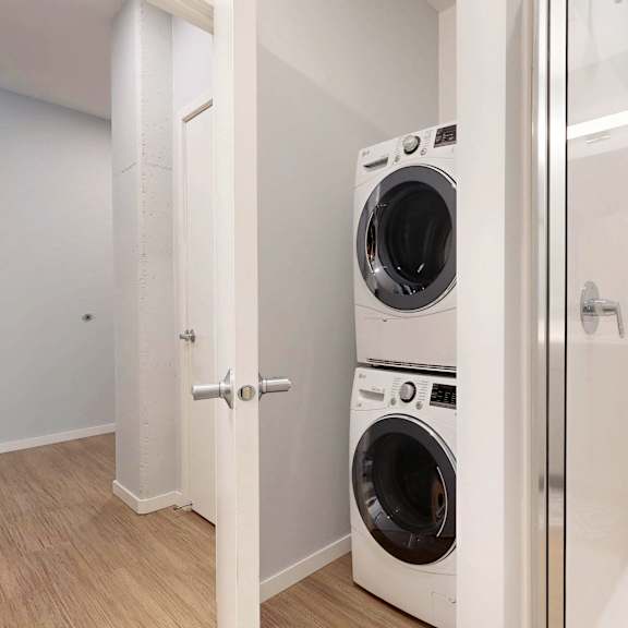 Thumbnail 6 of 8 A white washing machine and dryer in a small laundry room.