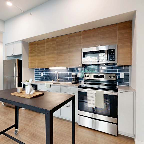 Thumbnail 7 of 8 A modern kitchen with a black table and stainless steel appliances.