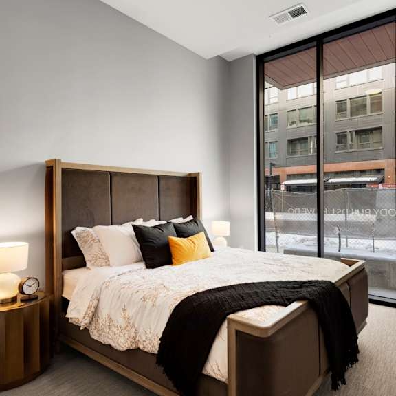 Thumbnail 6 of 7 A bedroom with a large bed and a window overlooking a city street.