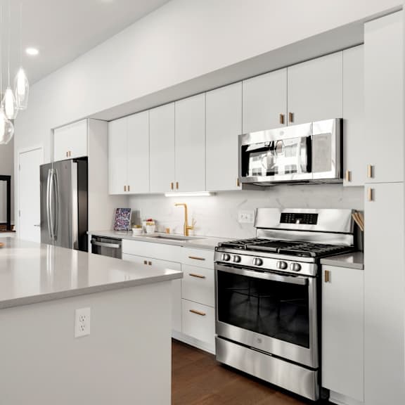 Thumbnail 4 of 7 A modern kitchen with a white countertop and stainless steel appliances.