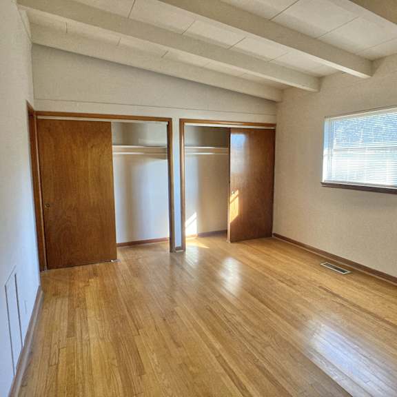 an empty living room with wooden floors and a window