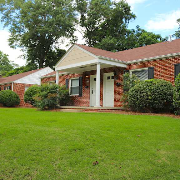the front of a brick house with a green lawn