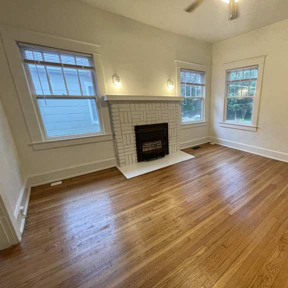 an empty living room with wood floors and a fireplace