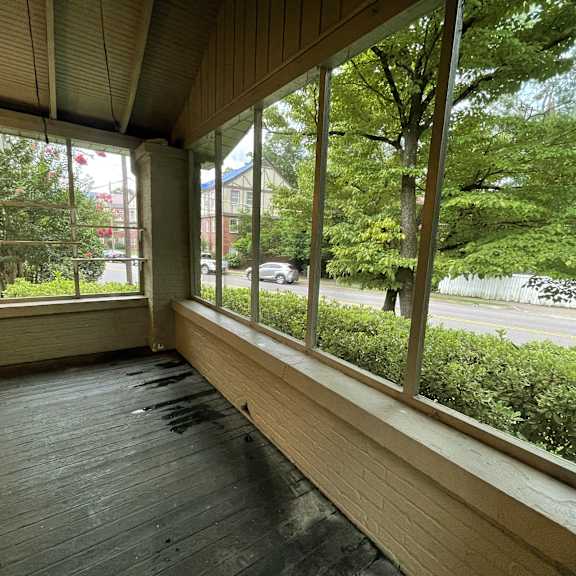 a large porch with large windows overlooking a street and trees