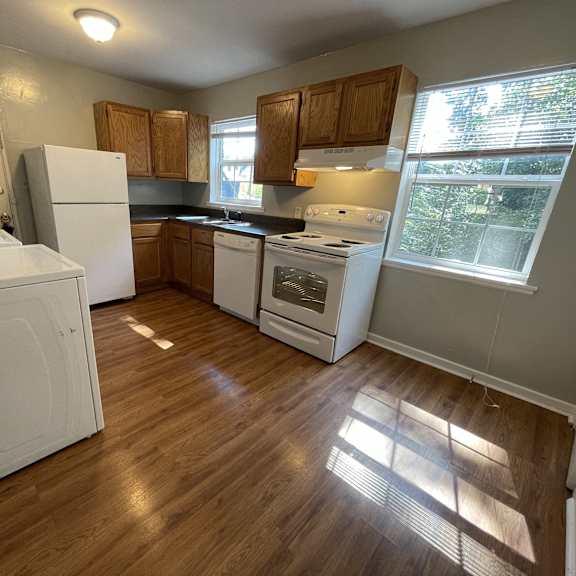 an empty kitchen with wood floors and white appliances