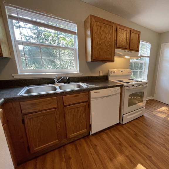 an empty kitchen with wooden flooring and a window
