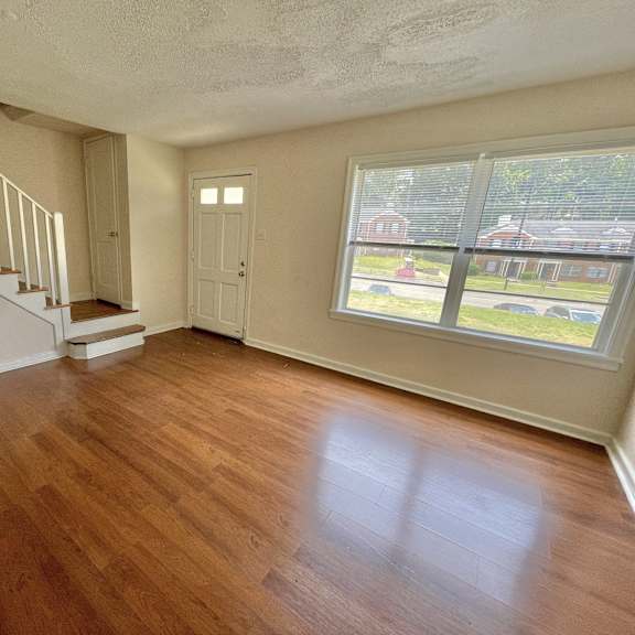 an empty living room with a hard wood floor and a staircase