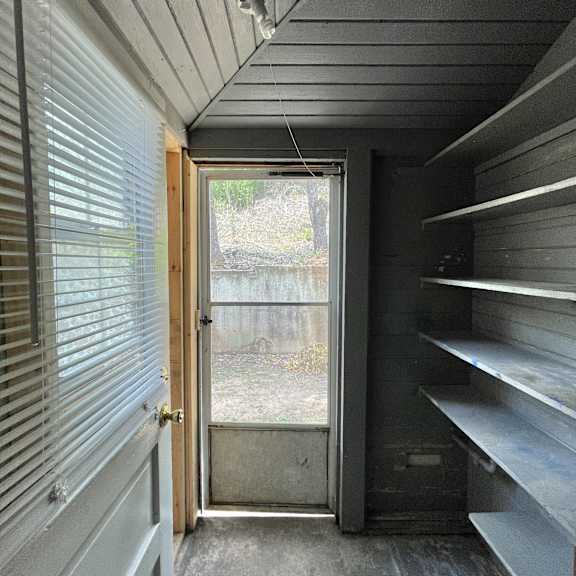 the inside of a tiny house with a door and shelves