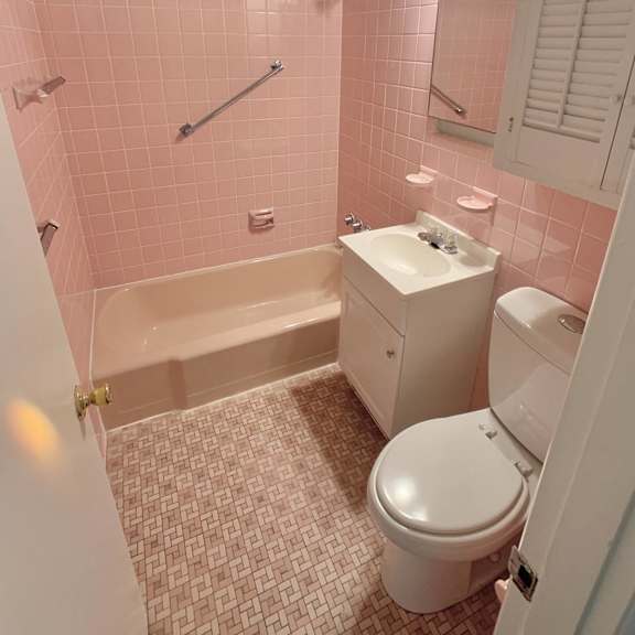 a pink bathroom with a toilet and a bath tub