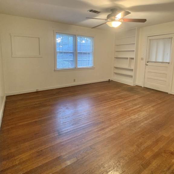 an empty living room with wooden floors and a ceiling fan