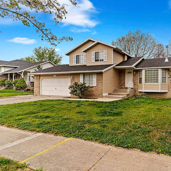 the front of a house with a lawn and trees