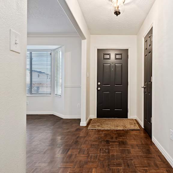 an empty entryway with a black door and a window