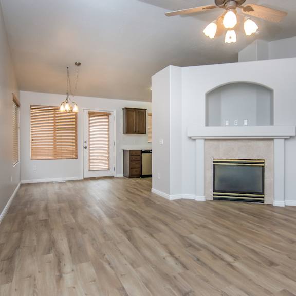 an empty living room with a fireplace and a ceiling fan