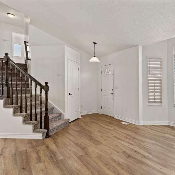 a spacious room with wooden floors and a staircase.