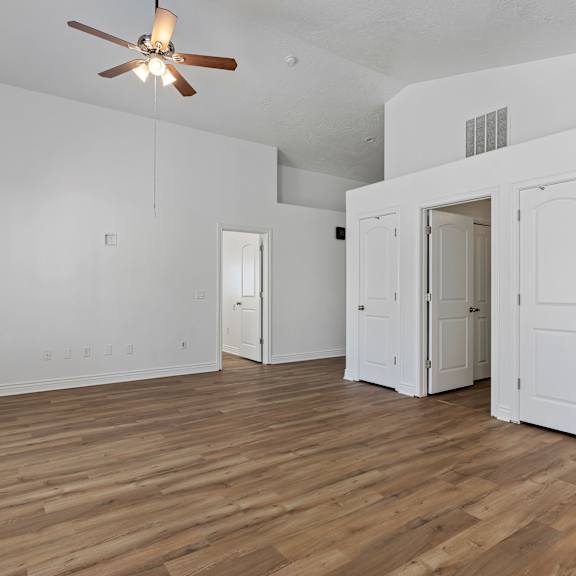 a room with a ceiling fan and wooden floors.