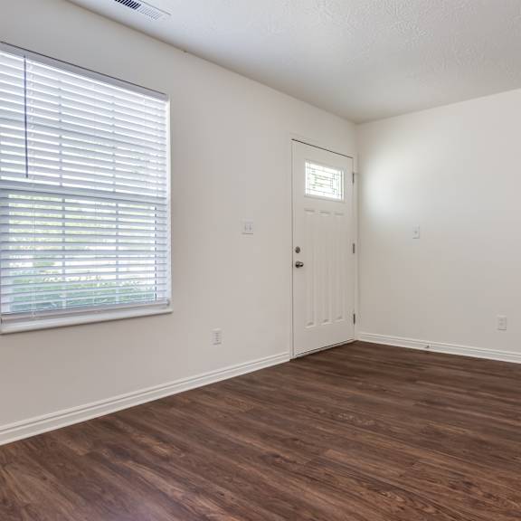 an empty living room with wood flooring and a window