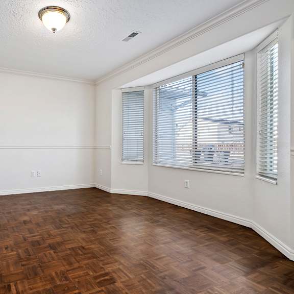 an empty living room with wood flooring and two windows