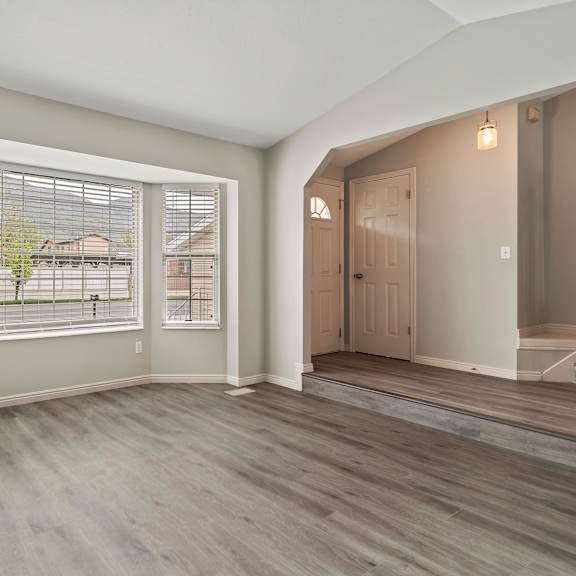 an empty living room with large windows and a door