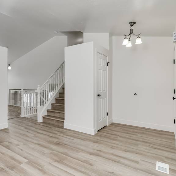 a white room with a staircase and a chandelier.