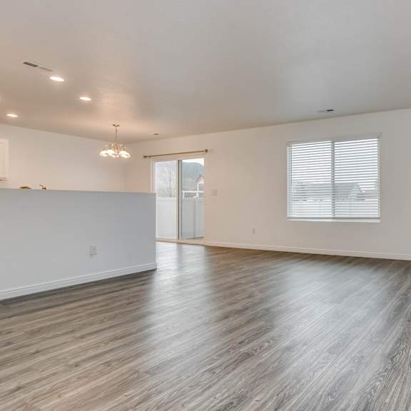 a room with wooden flooring and a window with blinds.