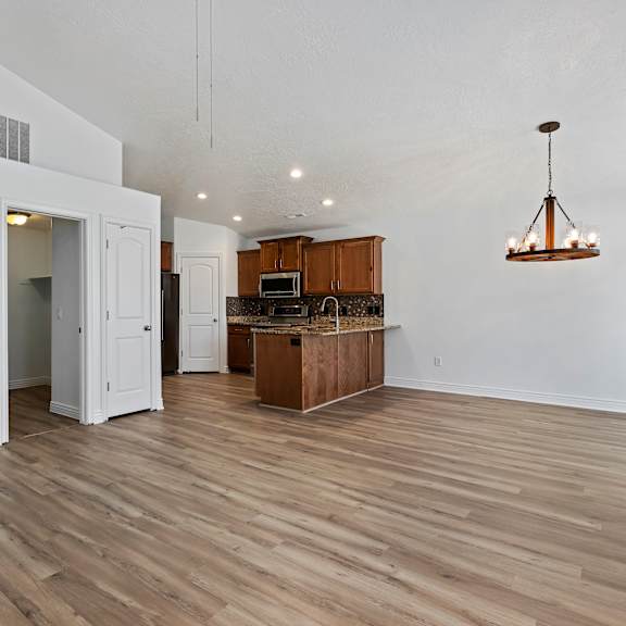 a room with a kitchen island and a hanging light fixture.