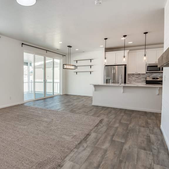 a spacious living room with a sliding glass door leading to a balcony.