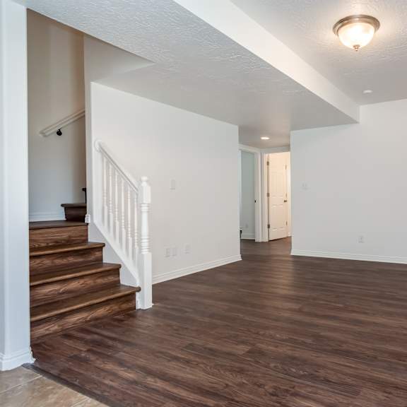 an empty living room with wood flooring and white walls
