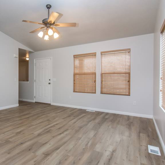 an empty living room with a fireplace and a ceiling fan
