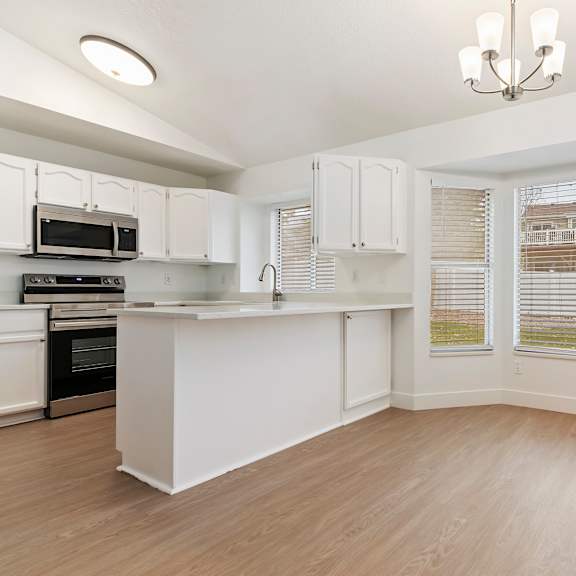 a kitchen with white cabinets and a wooden floor.