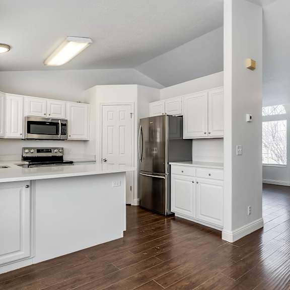 a kitchen with white cabinets and a wooden floor.
