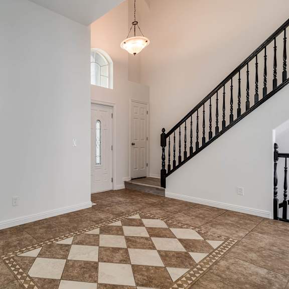the foyer of a house with a staircase and a large window