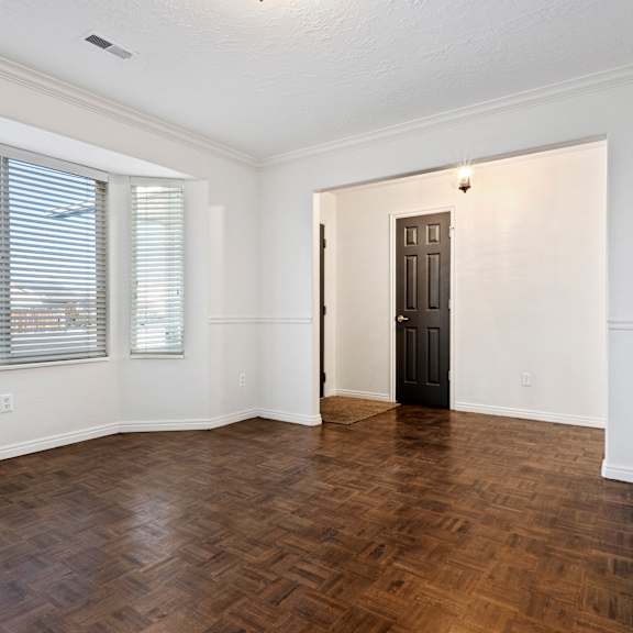 an empty living room with a large window and a wooden floor