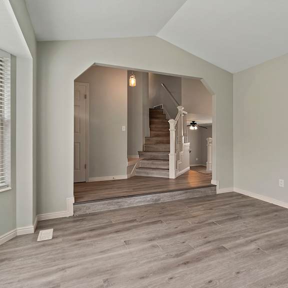 an empty living room with a staircase in the background and a window