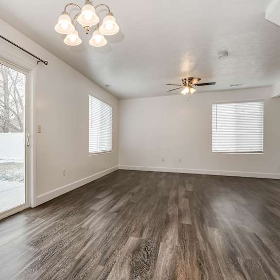 an empty living room with a sliding glass door to a backyard