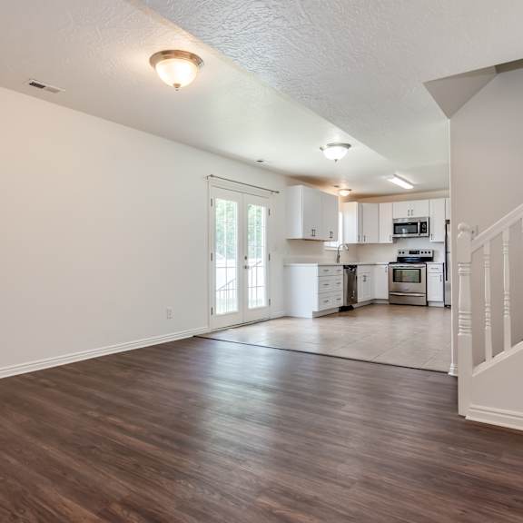 the living room and kitchen of a new home with white walls and wood floors