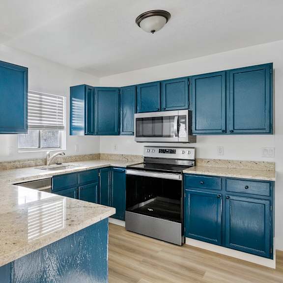 an empty kitchen with blue cabinets and marble counter tops